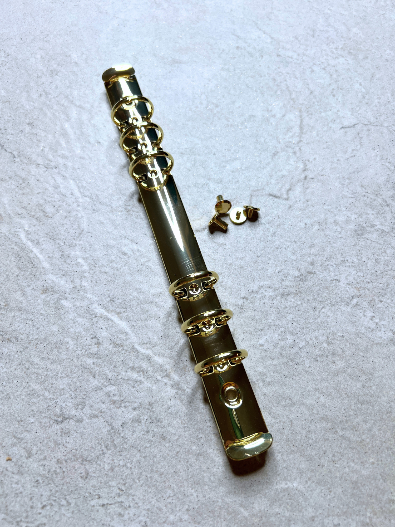 Gold-colored binder clip with decorative elements on a light gray background by Pop In Planner from www.popinplanner.com