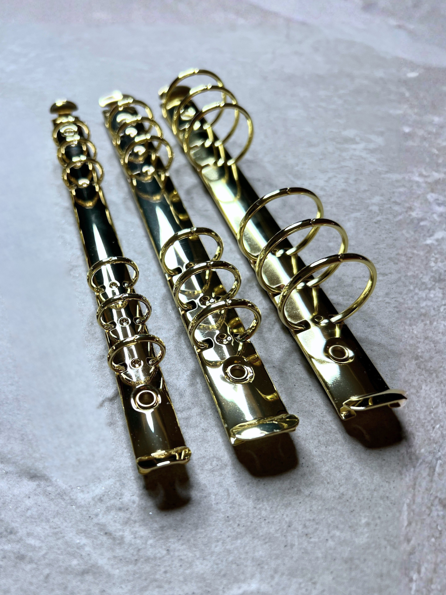 Three gold binder clips on a light gray background by Pop In Planner from www.popinplanner.com